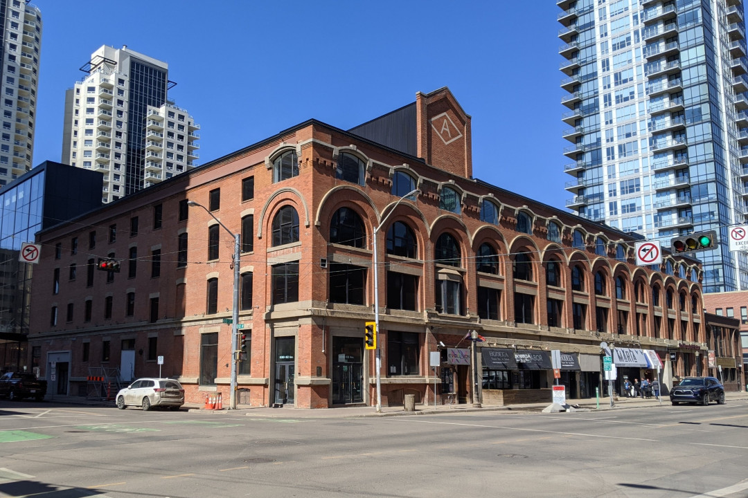 A downtown building made of brick and stone, with large arches built into the facade around the windows
