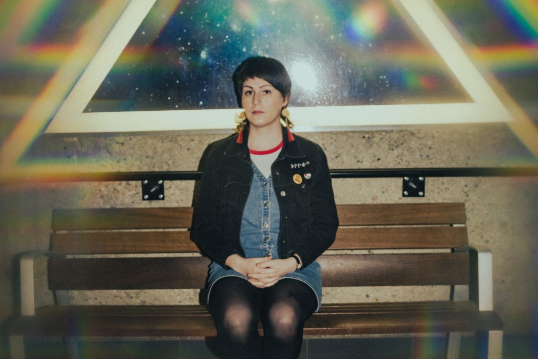 Why one musician has joined many others who aren't touring the U.S. Cassia Hardy seated on a bench while wearing two shades of denim and dangling earrings.