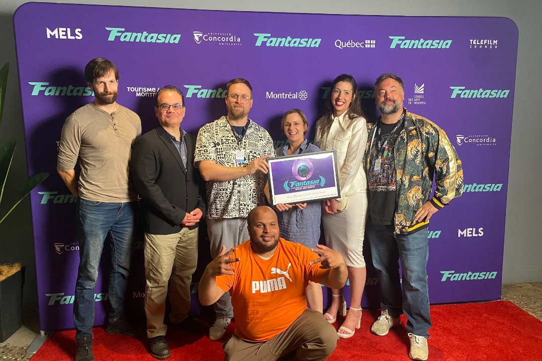 How an Edmonton comedian took his film to a global stage and screens A group of people gathered on a step-and-repeat, with two people in the centre holding up an awards plaque that says Fantasia.