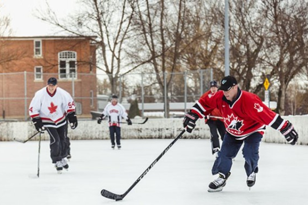 Skaters play hockey on an outdoor ice rink at a community league.