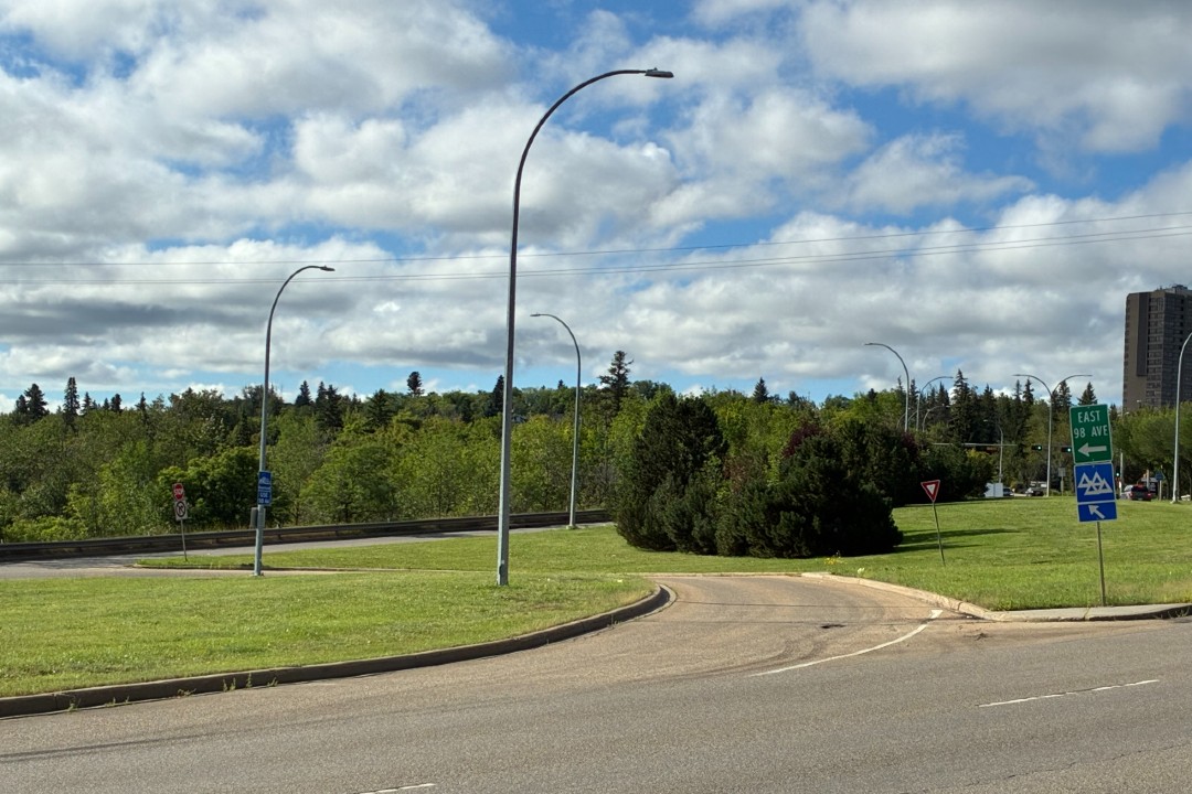 Grassy medians, trees, and street signs on a multi-lane street.