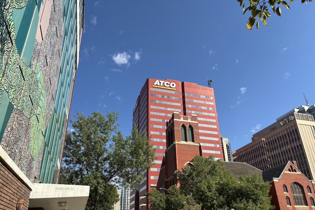 A cityscape with buildings and trees. At the centre of the picture is a dark red building with an ATCO sign at the top.