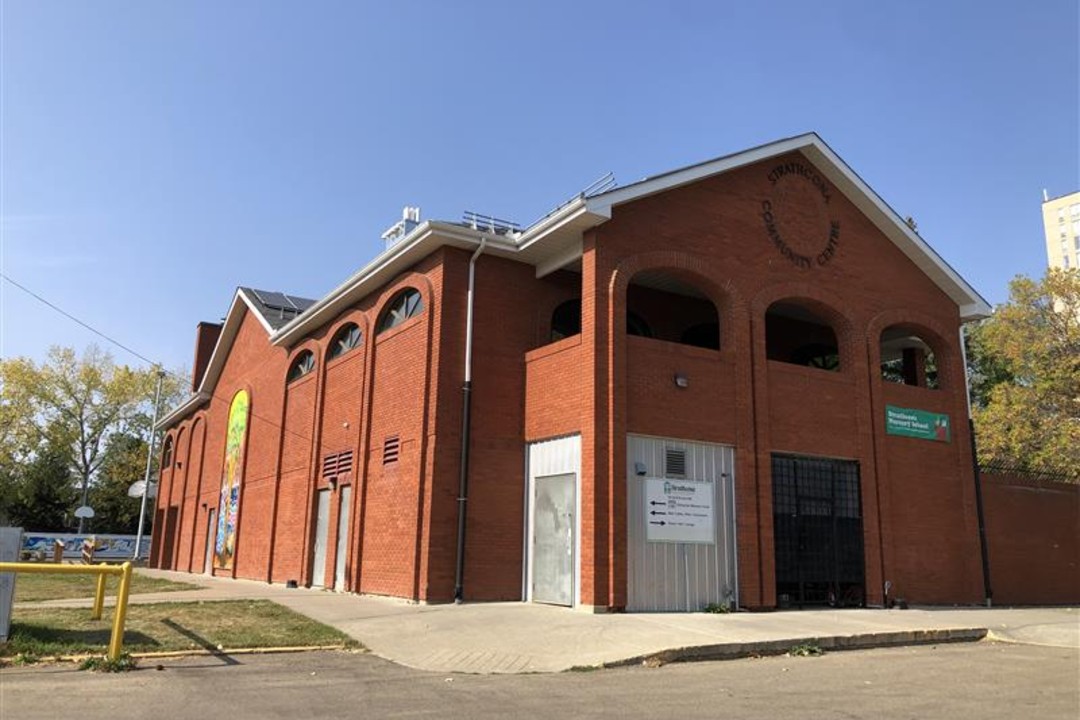 A two-storey brick building with a colourful mural on one side.