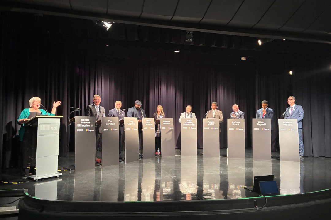 Karen Unland speaks at a podium next to 10 mayoral candidates.