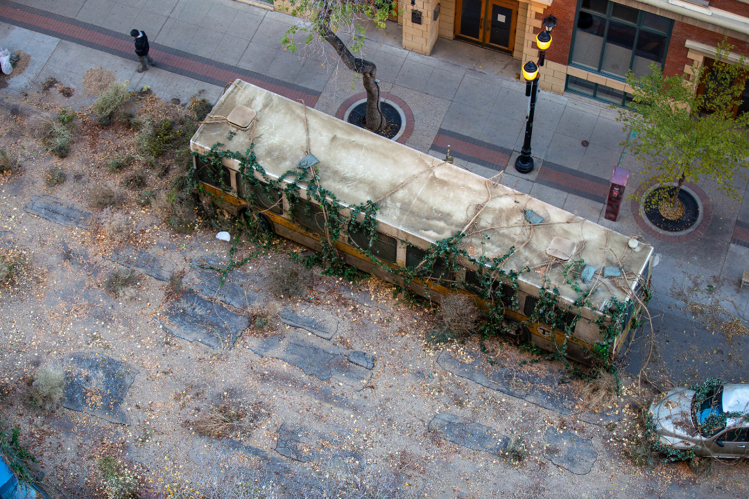 A bus covered in plant growth at a downtown movie shoot.