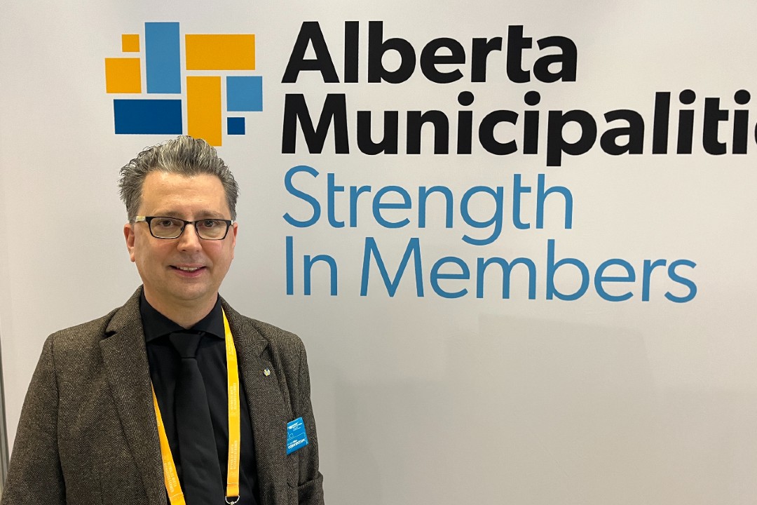 A man stands in front of a sign for Alberta Municipalities.
