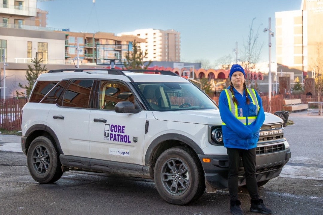 A worker wearing a blue-and-yellow uniform stands next to a vehicle with a decal that reads "Core Patrol."