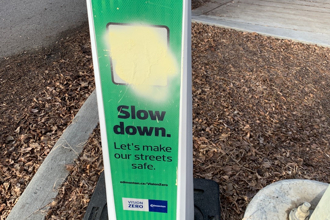 A city sign that encourages people to slow down but that has been vandalized