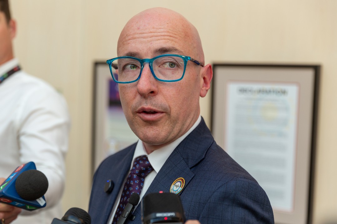 A man in a navy suit and blue glasses.