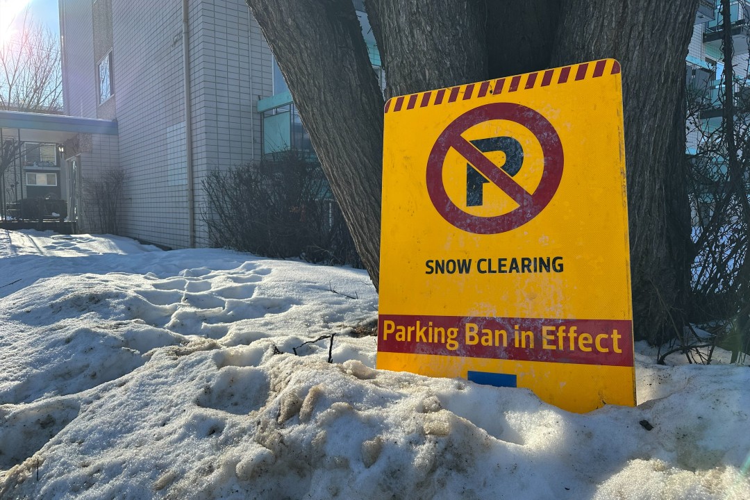 A bright yellow sign notifying residents of a snow clearing parking ban.