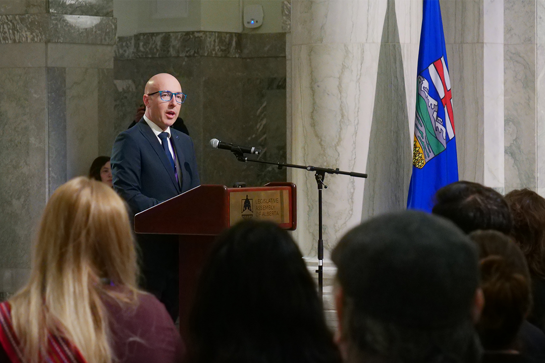 Mayor Andrew Knack speaks at a podium near an Alberta flag