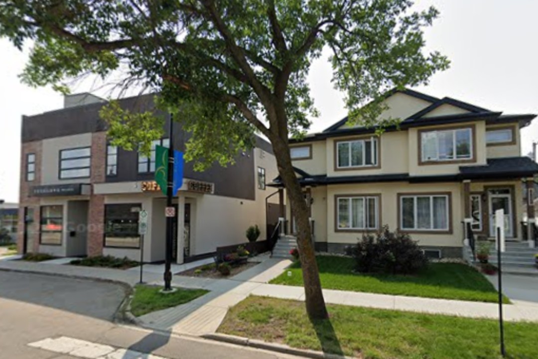 A two-storey single-family home beside a small commercial building with a coffee shop.
