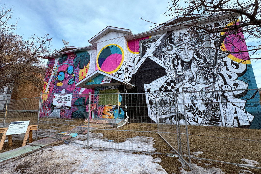 A boarded up apartment building covered in mural art