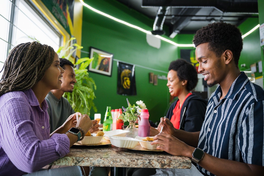 Four people gathered around a table with food and beverage.