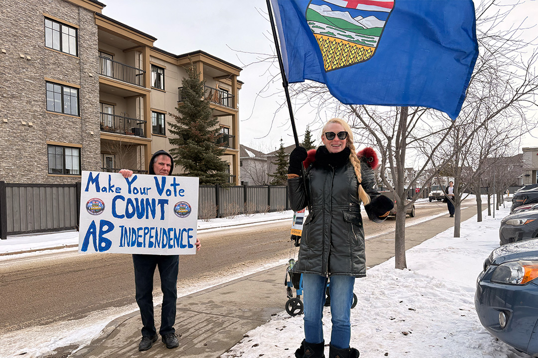 Two Alberta separatist canvassers, one holding an Alberta flag and another holding a sign