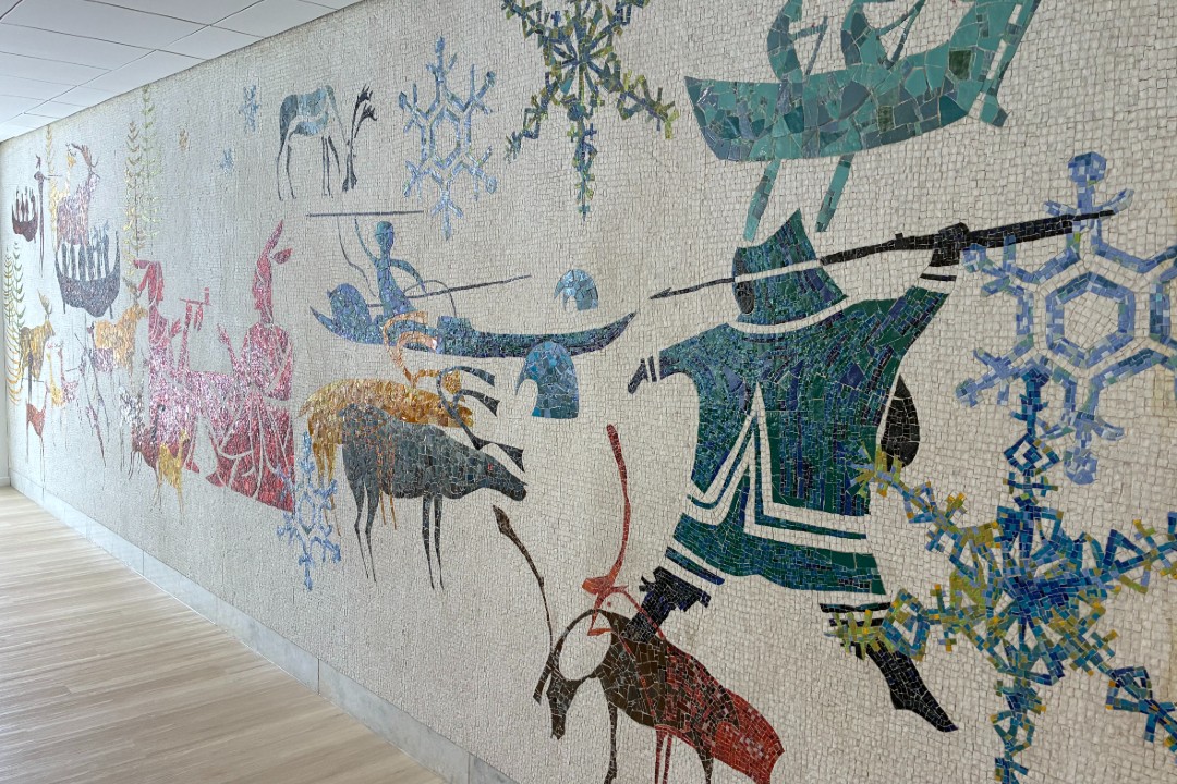 A mosaic depicting Inuit hunters, two figures in a canoe, caribou, among other pictures