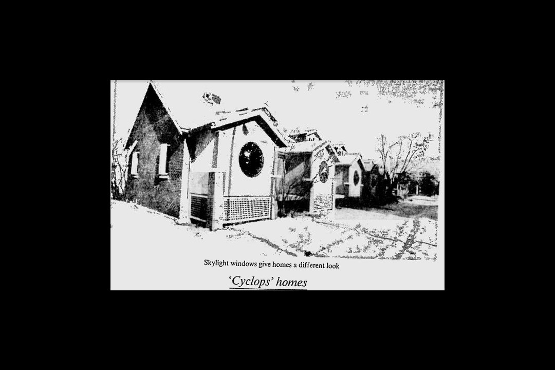 A newspaper clipping of a picture of townhouses with round, convex windows above a caption calling them 'Cyclops' homes.