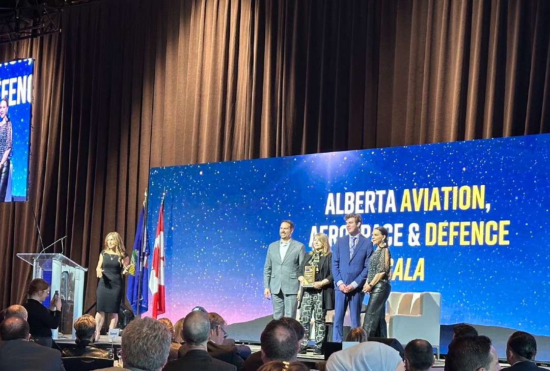 Five people gathered on a stage in front of a backdrop that reads Alberta Aviation, Aerospace and Defence gala