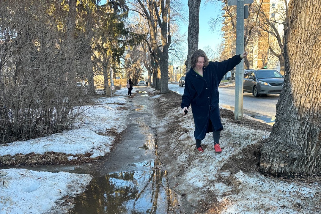 A woman walks on a windrow to avoid a puddle.