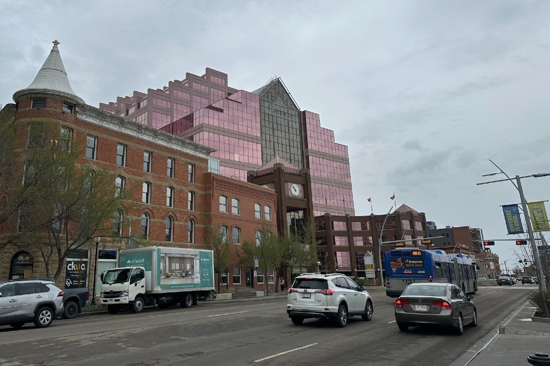 The brick CKUA building in front of the pink Canada Place building.