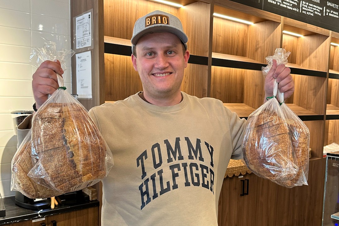 Milos Cvijanovic holds up two bags of bread inside Brio Bakery