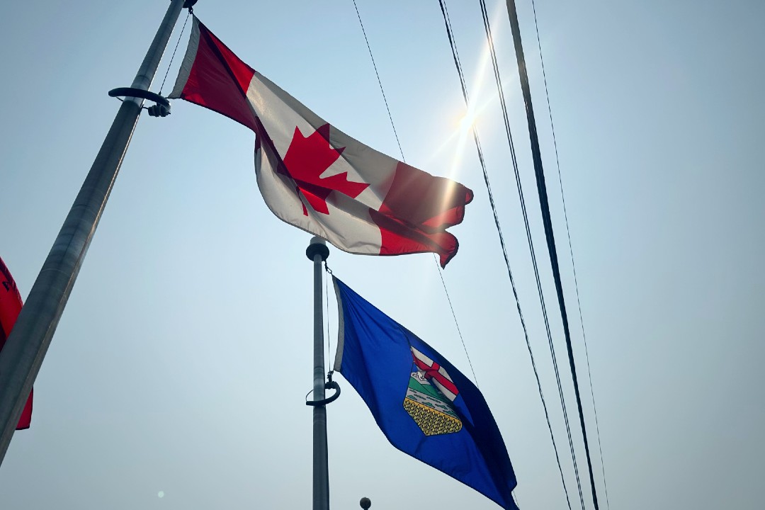 The Canadian and Albertan flags flap in the wind