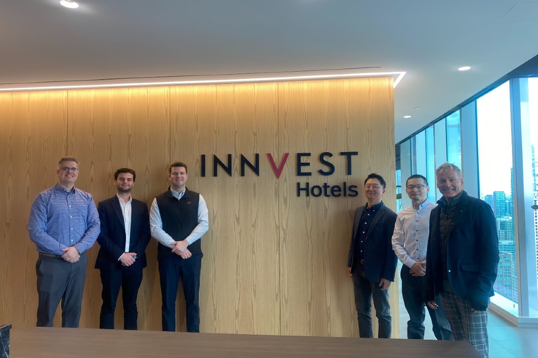 Six people gathered around a sign that says InnVest Hotels