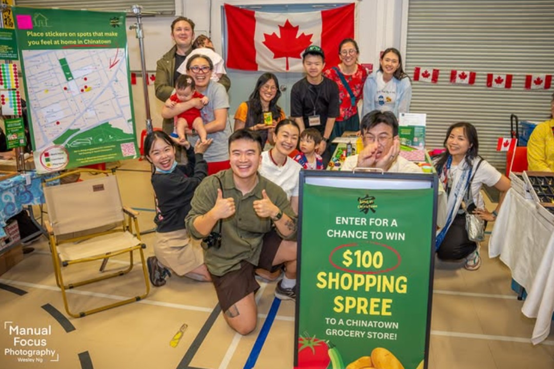 A dozen people pose at a booth, collecting feedback
