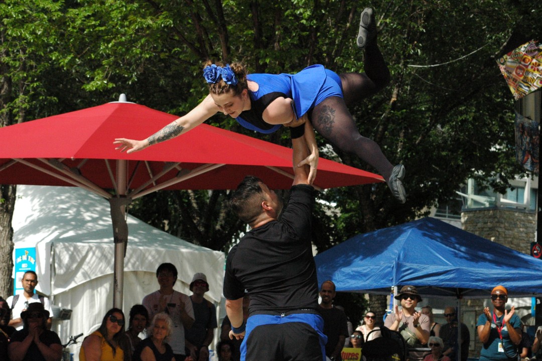 An acrobat balances on her partner's palm while spectators watch