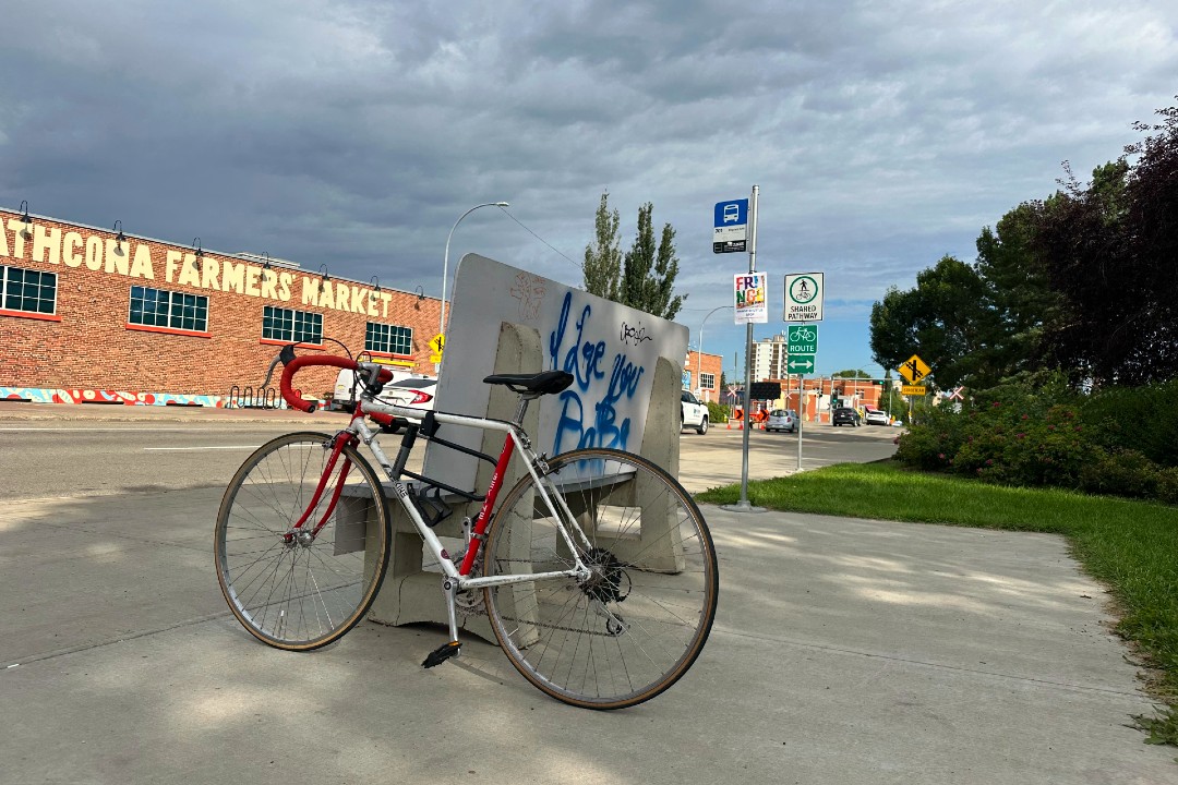 A bike leans against a bench at a bus stop