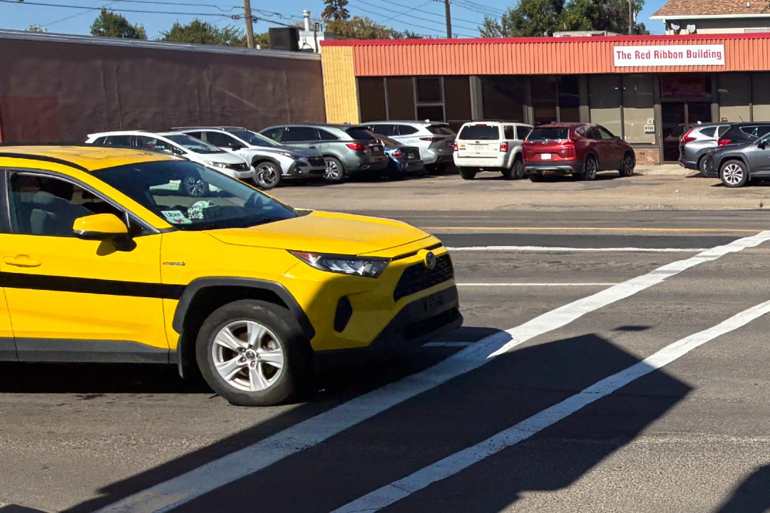 A taxi-yellow car with an Uber sticker on its windshield