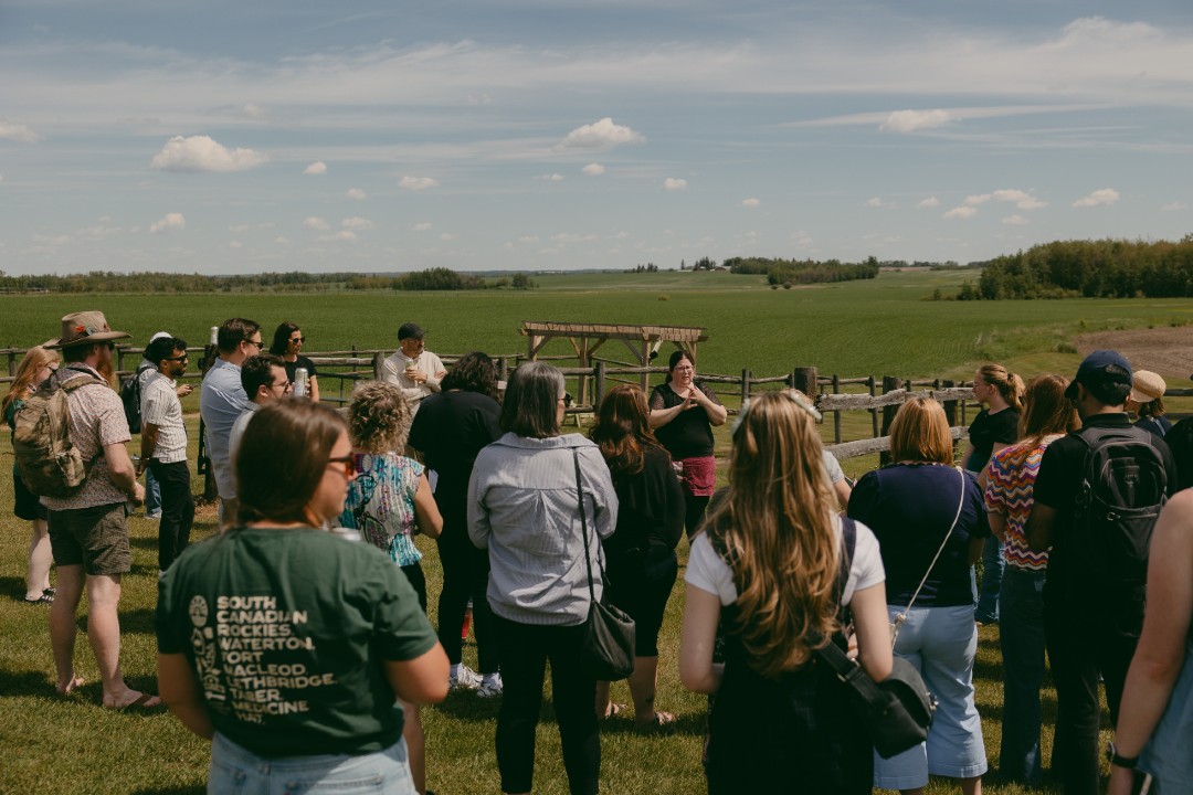 A crowd gathered at a verdant farm under a sprawling sky