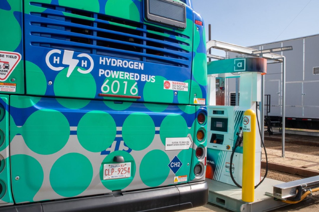 A hydrogen-powered bus next to a fuelling station