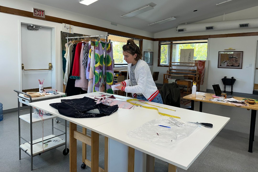 A person stands at a workbench with fabric