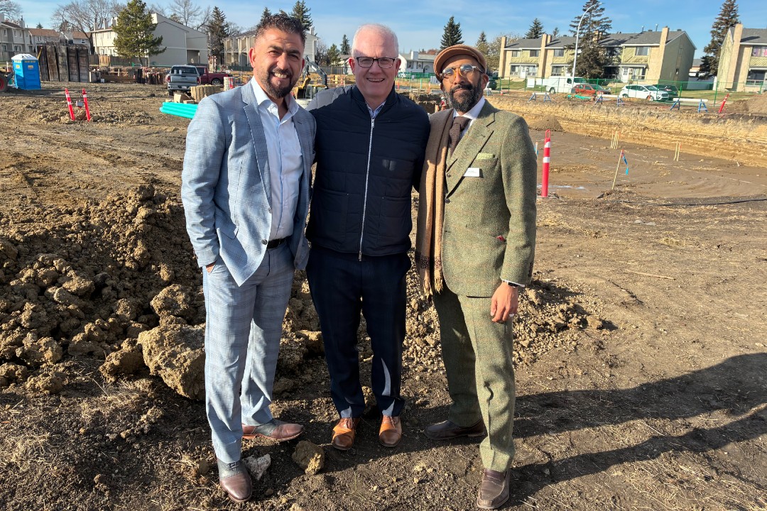 Three men pose at a construction site