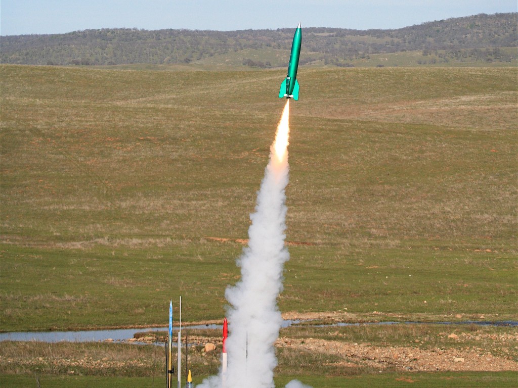 A green rocket takes off into the sky